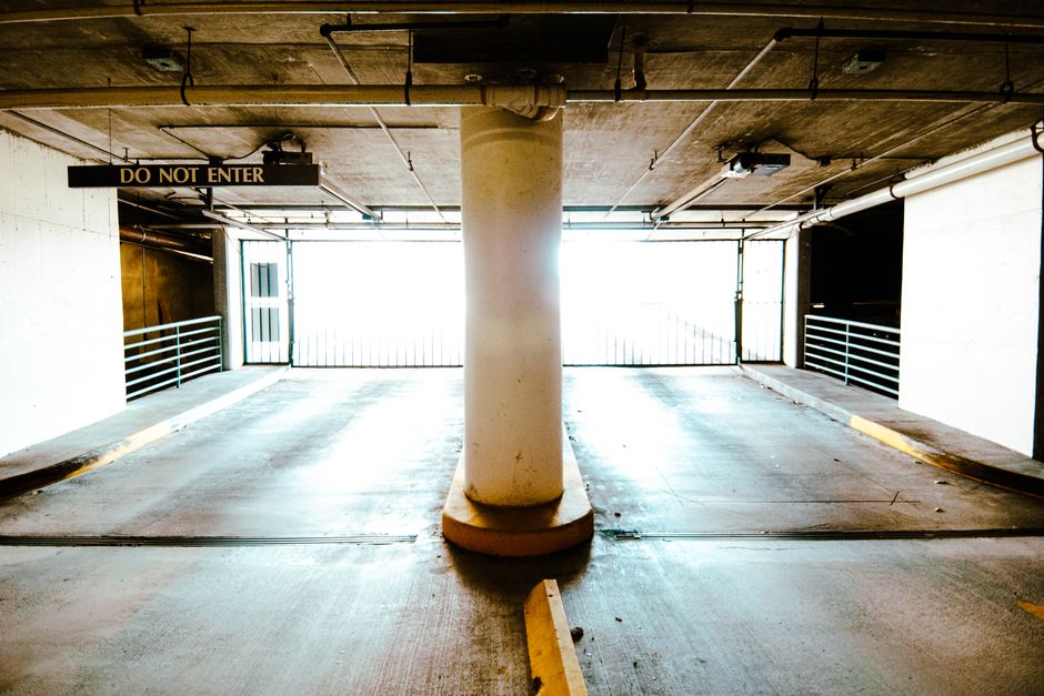 A brightly lit empty parking garage with a central pillar and 'Do Not Enter' sign.