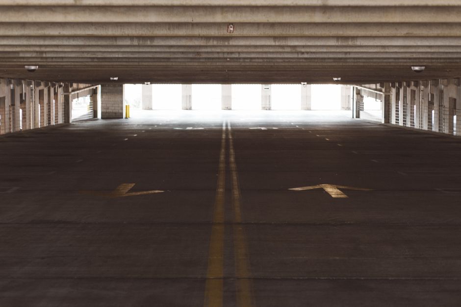 Spacious and empty parking garage interior with directional arrows on the floor, modern architecture.