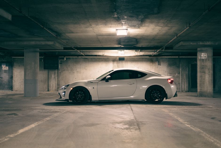 White sports car parked in a dimly lit underground garage, emphasizing modern automobile design.